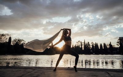 Silhouette of a person in a balancing yoga pose against a soft-lit background.